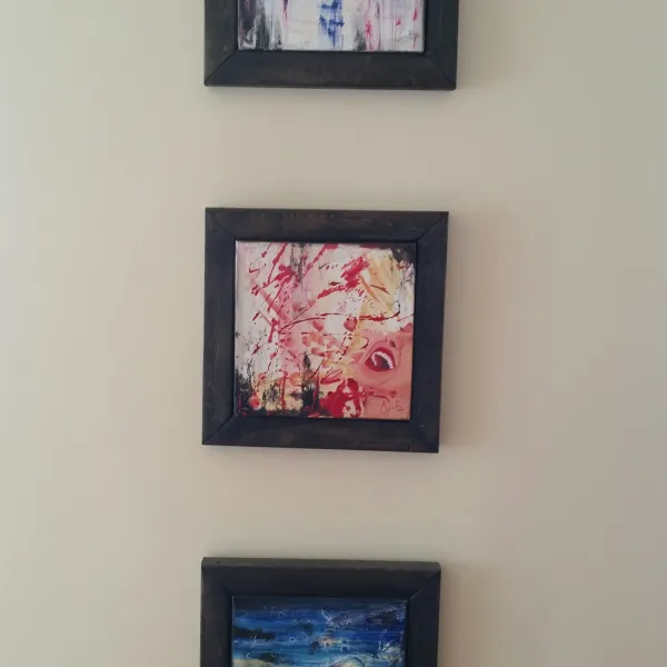 Three small paintings are hanging on the wall.